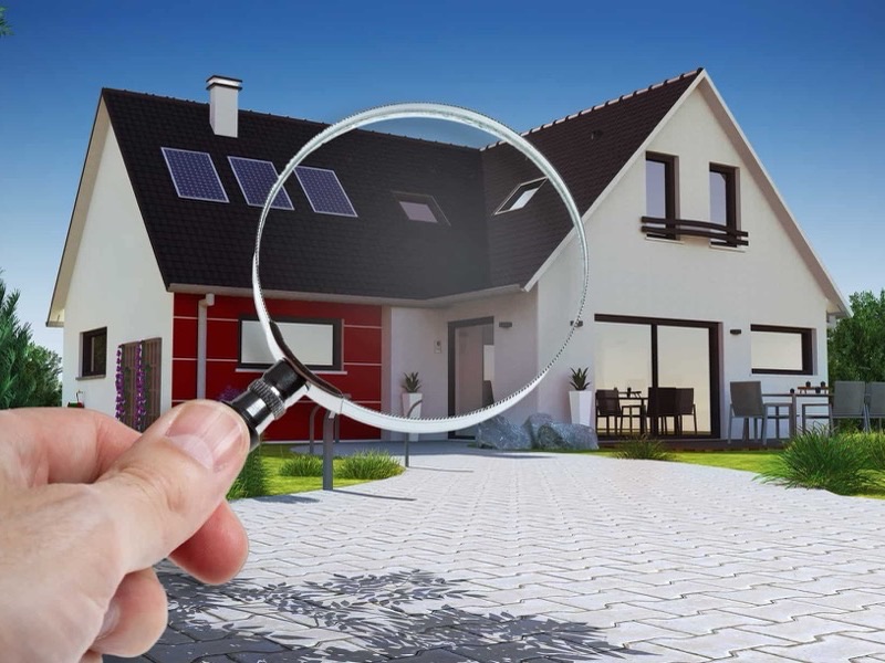 A residential home being inspected through a magnifying glass — illustrating professional radon testing for real estate transactions